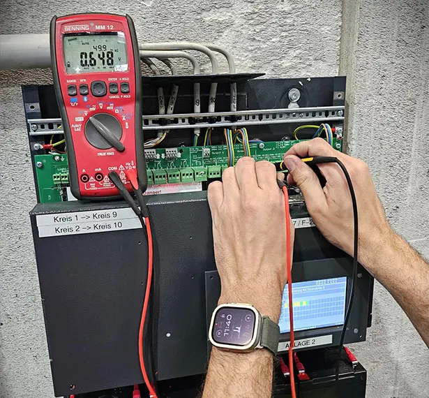Servicetechniker Elektro misst an einer Anlage im Technikraum
